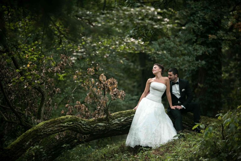 woman in white wedding dress with groom standing behind her in a beautiful garden