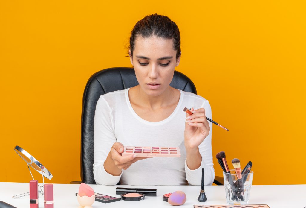 woman with an array of make up products in front of her