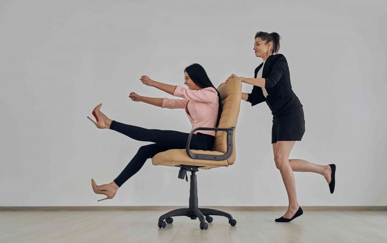 Two girls playing a rolling chair.