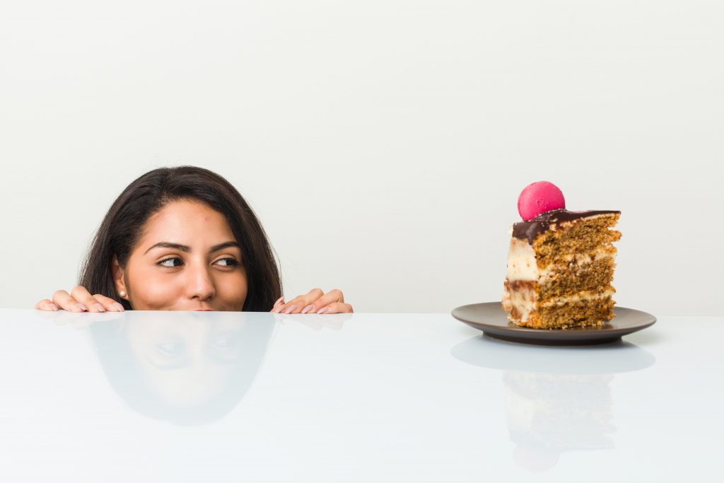 A woman starring at a plate with chocolate cake.