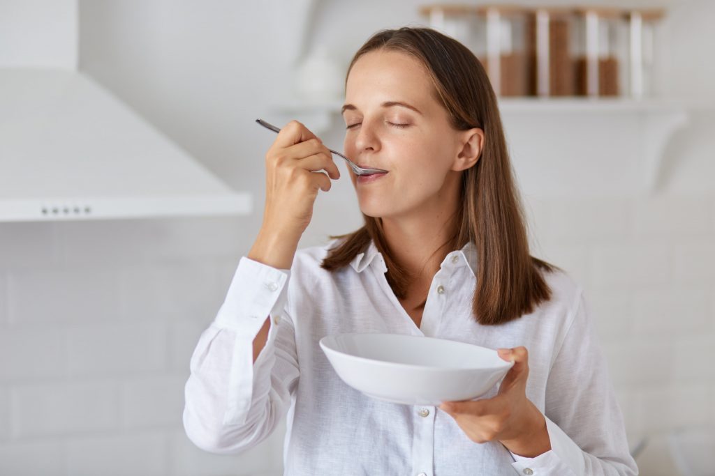 A woman eating from a white bowl.