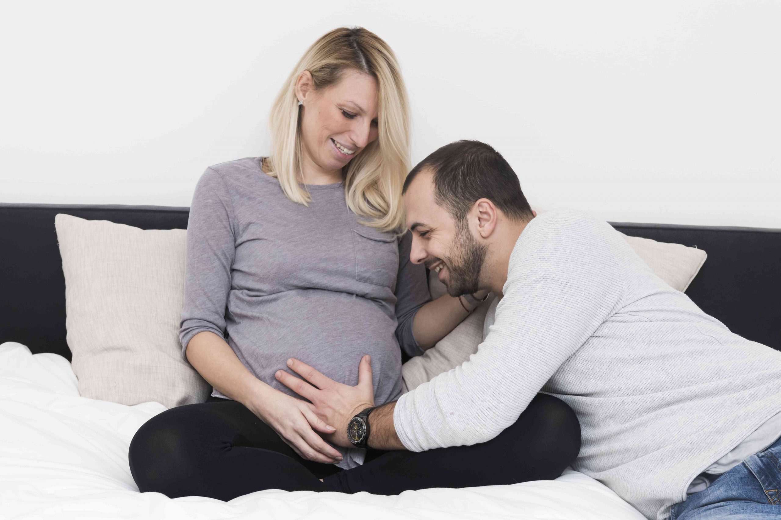 A father embracing his child in the womb, while the mother watches and smiles.