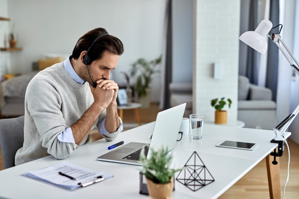 a man sitting at his desk with lap top focusing seriously on his work without distractions