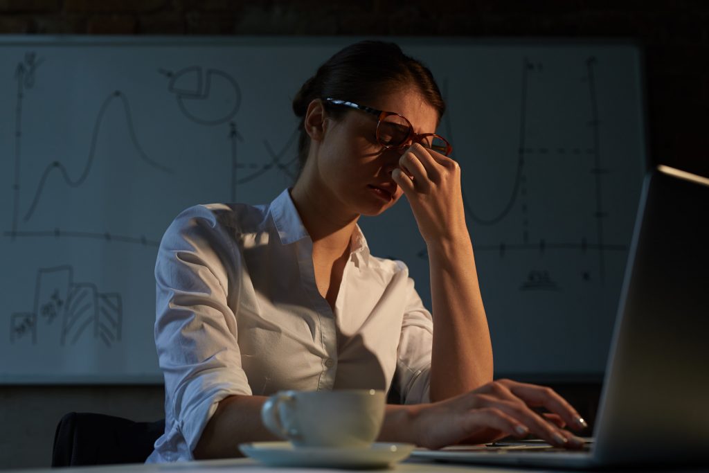 woman working late into night feeling very tired
