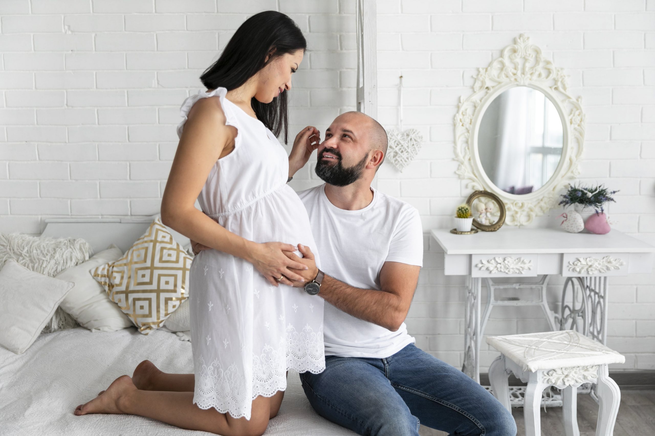 a pregnant person and person sitting on a bed