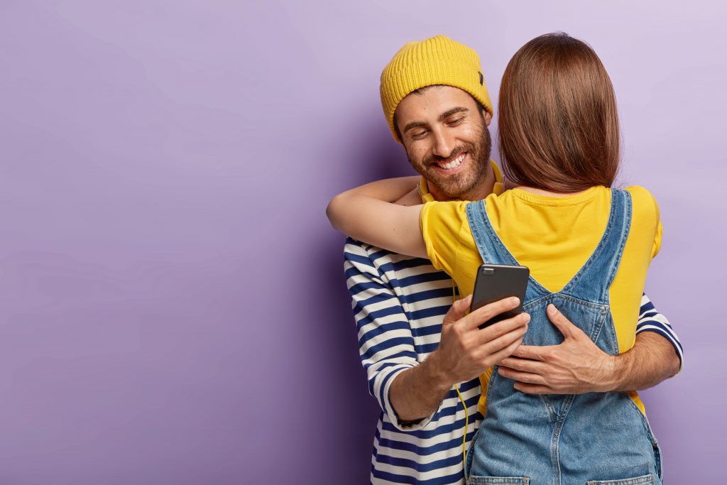 man hugging his lover and texting another girl friend behind his lover's back 