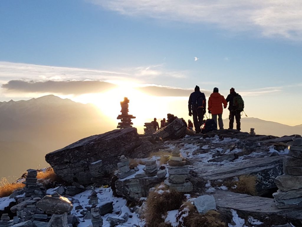 Three people sawing the sunset at top of the mountain top