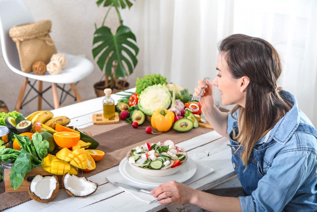 woman eating a whole lot of health fruits and vegetables