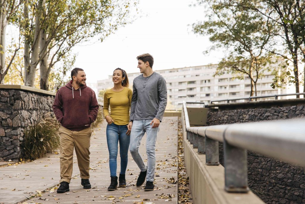 two male and one female waking together in a bridge 