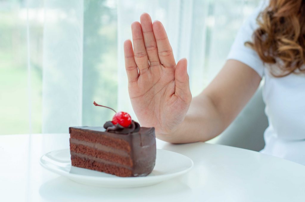 women showing hand stop sign to  piece of cake 