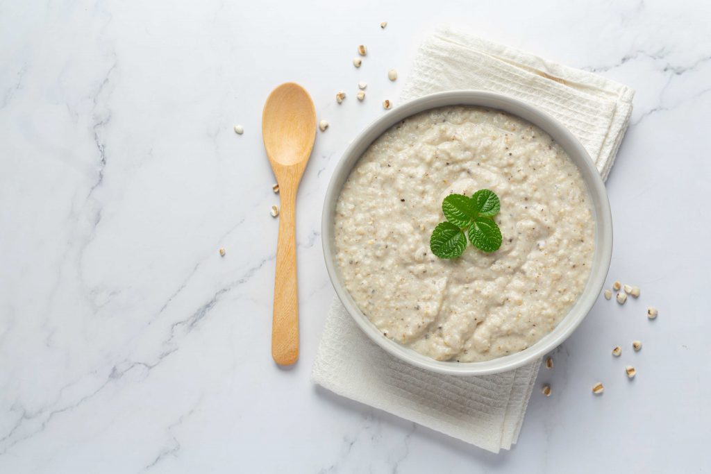 hulled barley porridge in a white bowl with herb on top 