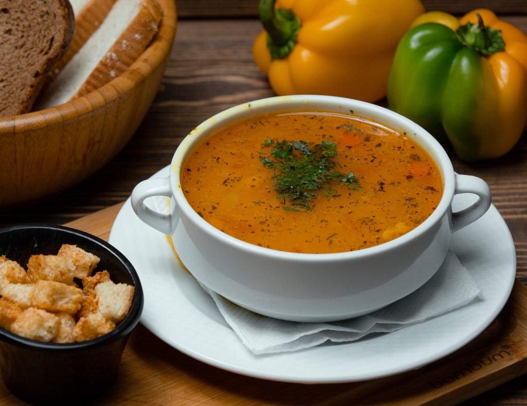 lentil soup in a white bowl with herbs on top 