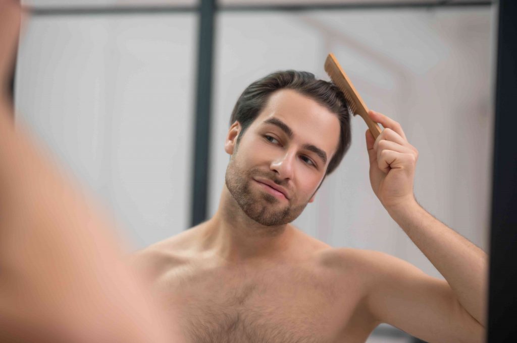 man brushing his hair as he looks at himself in the mirror