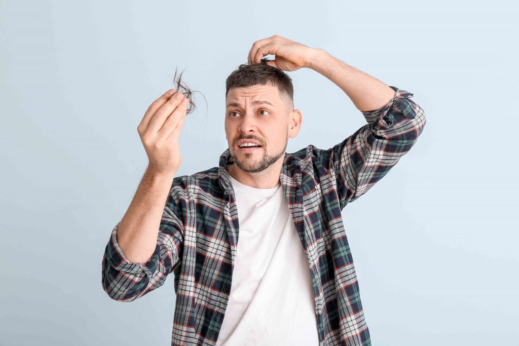 man worried at his hair loss has a tuft of hair in his hand