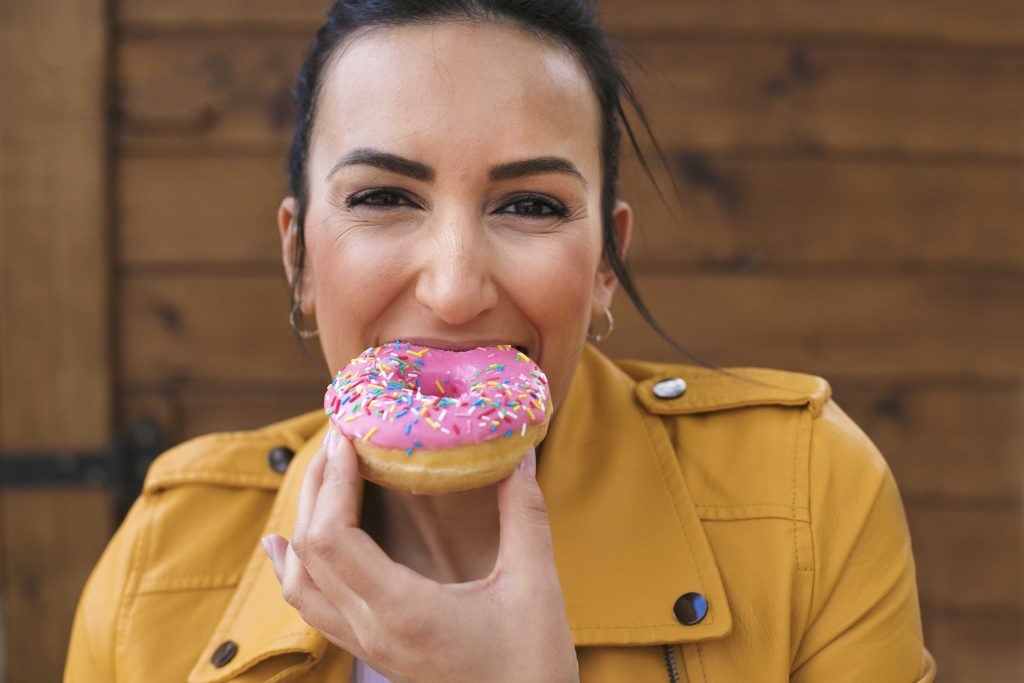 prediabetic woman eating a donut and happy