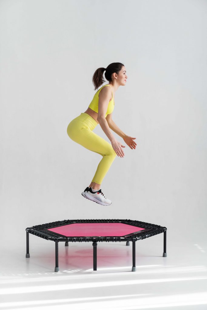 cheerful woman wearing sport wear jumping on a trampoline