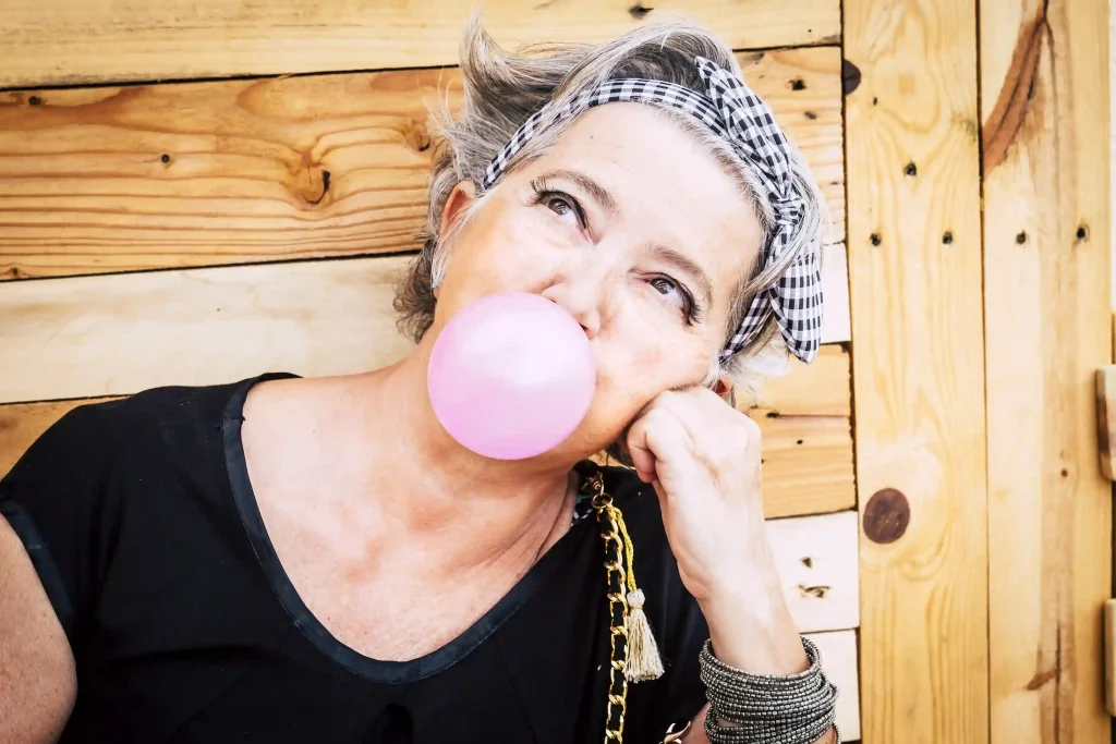 elder woman chewing gum and making bubble 