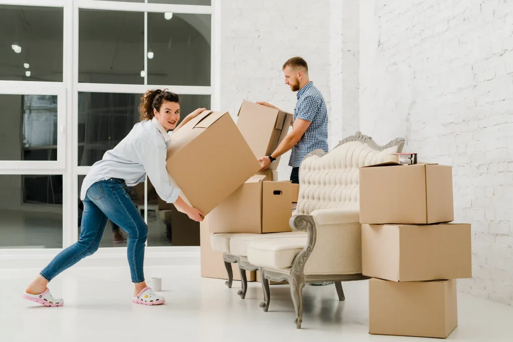 man and woman moving into a new house, lifting card board boxes, with strong core muscles. 